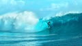 Giant emerald tube wave crashes wildly behind extreme pro sportsman surfing.