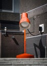 Giant enormous bright red desk lamp light with big bulb plugged into external wall of building at top of steps. Royalty Free Stock Photo