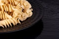 Giant fusilli pasta on black plate and stone background