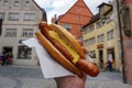 Giant German sausage with mustard in a bun, held up high