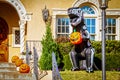 Giant Halloween inflatable skeleton dinosaur roaring and holding pumpkin in front of upscale residential house decorated with jack