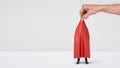 A giant hand taking off a red drapery from a hidden businessman on white background. Royalty Free Stock Photo