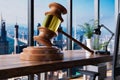 Giant judge gavel law concept; office chair in front of modern workspace with skyline view; lawsuit concept; 3D Illustration