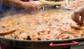 Giant paella during cooking.Adding shrimp and shellfish Royalty Free Stock Photo