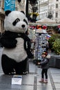 A giant Panda figure outside shops and Restaurants in main city pedestrian street, with exciting little girl