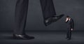 Giant person stepping on a little businessman concept Royalty Free Stock Photo