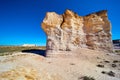 Giant pillar of white and gold brown rock in desert landscape against blue sky Royalty Free Stock Photo