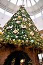 A giant pine Christmas tree decorated with colorful balls, bows, gifts and lots of led lights