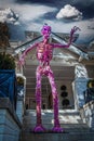Giant purple skeleton monster with pumpkin head stands on steps towering over vintage home decorated for Halloween