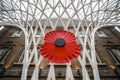 Giant red poppy mounted to abstract curved roof pattern architecture in Kings Cross train station concourse interior departure