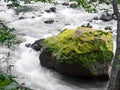 Giant rock with green moss in fast flowing river at Ryu Sei waterfall, Hokkaido, Japan.