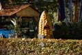 Giant scary Mr. Corn peeks out from behind a hedge.