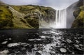 The giant skogafoss waterfall becomes frozen river with black rocks ground.