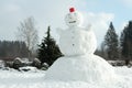 A giant snowman with a red bucket as a hat in Northern European garden