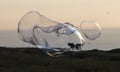 Giant soap bubble creature with iridescent rainbow colours during sunset