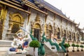 A giant statue in front of beautiful Thai style building in a Buddhist temple in Thailand.