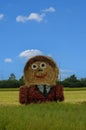 Giant straw doll with painted clothes in a harvested field