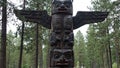 Giant totem pole with bear and fox carvings blending into pine forest Royalty Free Stock Photo