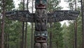 Giant totem pole with bear and fox carvings blending into pine forest Royalty Free Stock Photo