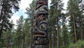 Giant totem pole with bear and fox carvings blending into pine forest Royalty Free Stock Photo