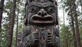 Giant totem pole with bear and fox carvings blending into pine forest Royalty Free Stock Photo