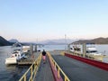 A man walking along a dock towards his boat facing the coast mountains, along the Sunshine Coast, outside Gibsons