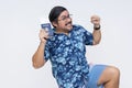 A giddy man in a Hawaiian shirt looking thrilled while holding a boarding pass and US passport, showing excitement for traveling. Royalty Free Stock Photo