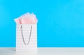 Gift bag with paper on white table against light blue background. Space for text Royalty Free Stock Photo