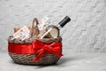 Gift basket with bottle of wine on light background