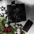 Gift in a black package with a black bow against the background of Christmas decoration