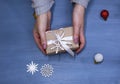 Flat lay of woman hands holding gift wrapped and decorated with bow on blue background with copy space