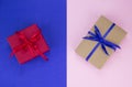 Gift with a blue and red ribbon on a double background. Kraft gift box with blue ribbon. Pink and blue background. Royalty Free Stock Photo