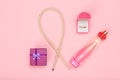 Gift box, beads, bottle of perfume and golden ring in box on a pink background. Women cosmetics and accessories.