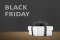 Gift box with black ribbon and Black Friday text on the black wall background
