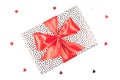 Gift box with black spots and red satin bow on a white background with glitter hearts. Festive concept Royalty Free Stock Photo