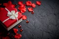 Gift box on black stone table. Romantic holiday background with rose petals Royalty Free Stock Photo