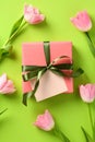 Gift box with blank greeting card mockup and tulips on green background. Happy Mothers Day concept Royalty Free Stock Photo