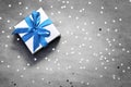 Gift box with blue ribbon on grey background with star.