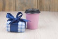 Gift box with blue ribbon and paper coffee cup on wooden background. Holiday concept with copy space. Discount gift for sale day Royalty Free Stock Photo