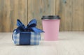 Gift box with blue ribbon and paper coffee cup on wooden background. Holiday concept with copy space. Discount gift for sale day Royalty Free Stock Photo