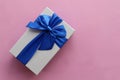 Gift box with blue ribbon on pink paper background. Mothers day present or birthday gift. Top view, copy space Royalty Free Stock Photo