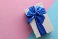 Gift box with blue ribbon on pink paper background. Mothers day present or birthday gift. Top view, copy space Royalty Free Stock Photo