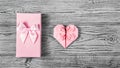 A gift box with a bow and a delicate pink heart made of paper on a gray background. Postcard heart of origami. Copy space