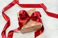 Gift box with bow made with red satin ribbon on a table Royalty Free Stock Photo