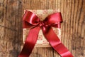 Gift box with bow made with red satin ribbon on wooden table Royalty Free Stock Photo