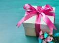 Gift box with bow ribbon and pink flowers on turquoise table Greeting card for Birthday. Generative AI Royalty Free Stock Photo