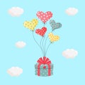 Gift box with a bow tied to heart inflatable gel balloons in the sky. Birthday party or Valentine\'s day concept Royalty Free Stock Photo