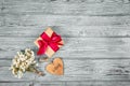 Gift box with bow and wooden heart on a gray wooden background. Copy space