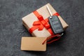 Gift box with car keys with remote control alarm system with red ribbon bow and label. Royalty Free Stock Photo