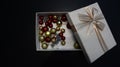 Gift box with Christmas globes inside against dark background